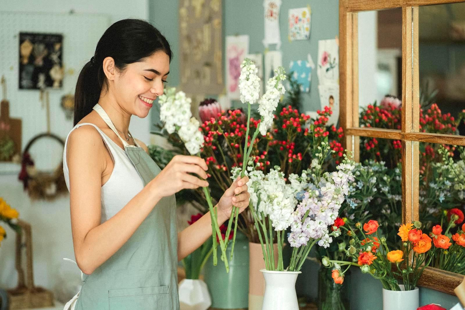 Happy woman business owner arranging flowers in her Marin County flower shop, representing successful local businesses with improved SEO.