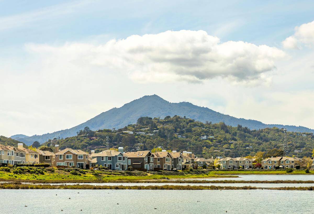 A stunning view of Mount Tamalpais from Corte Madera, Marin County, featuring a green field, blue sky, and water.