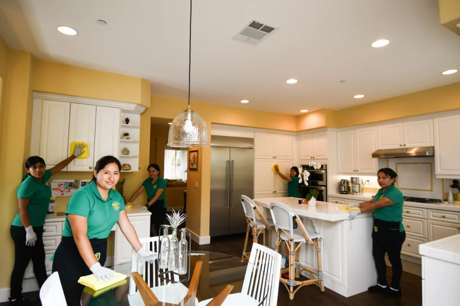Team of women in green uniforms cleaning a kitchen as part of Organic Cleaning Supreme’s eco-friendly service.
