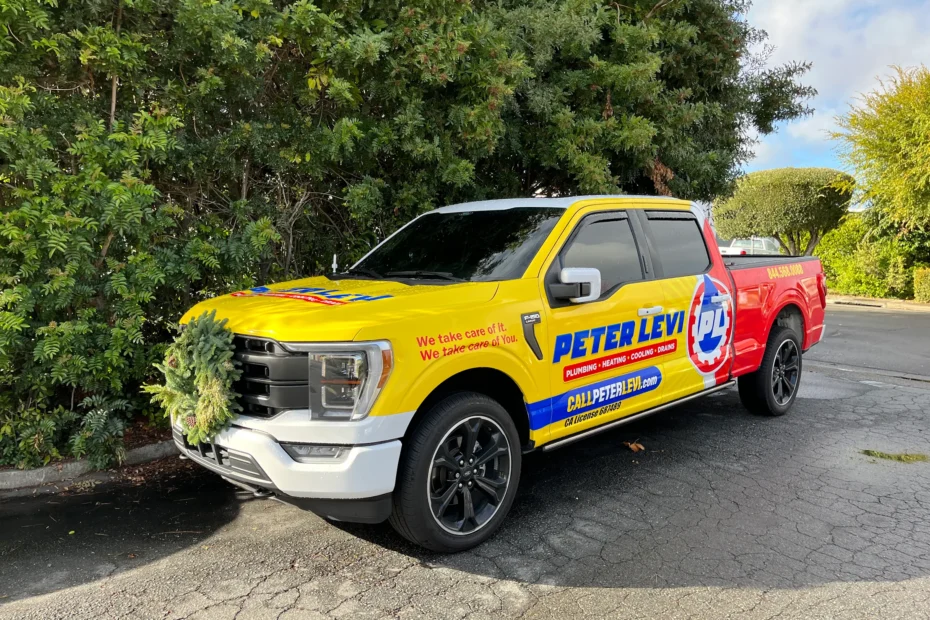 Peter Levi Plumbing branded work truck in bright yellow and red colors parked outside a Marin County service location.