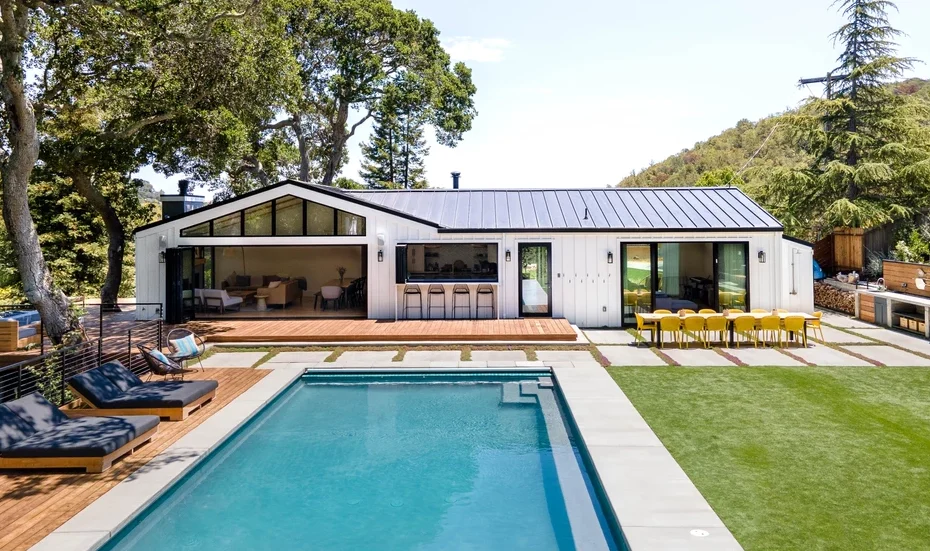 Modern white home with black metal roof, spacious backyard, and pool built by G Family Construction.