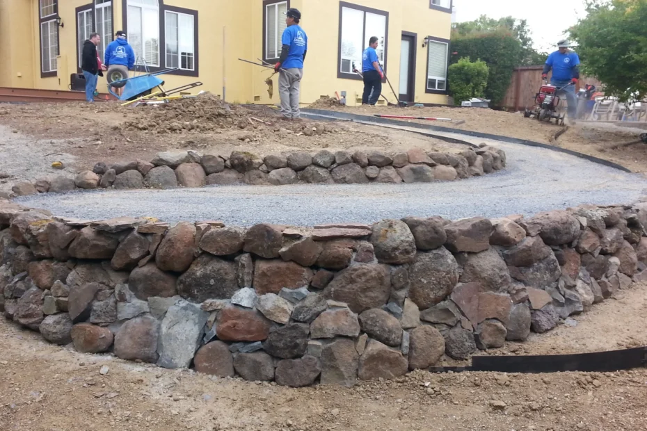 Beautifully landscaped yard featuring rockwork short wall, stone pathway, and flat seating area.